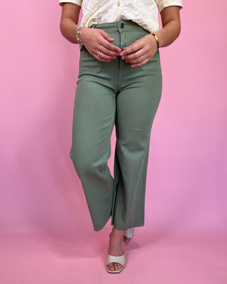 Person wearing green pants on a pink background