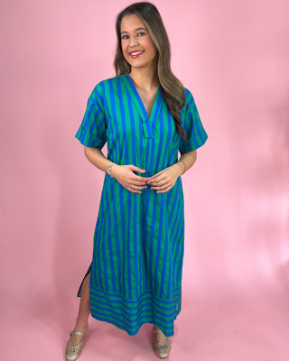 Woman wearing a blue and green striped dress against a pink background