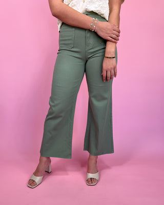 Person wearing green pants on a pink background