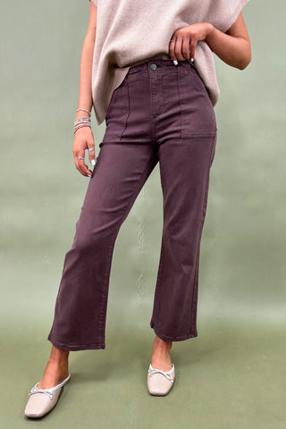 Person wearing purple pants and a beige top on a green background