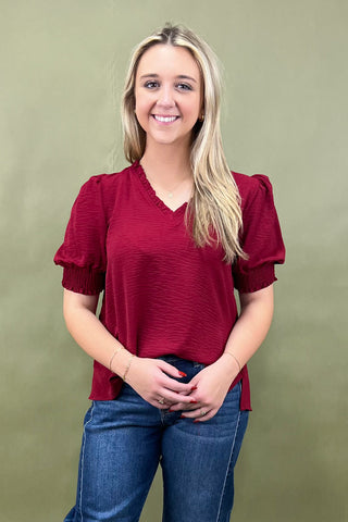 Woman wearing a red blouse and blue jeans against a green background