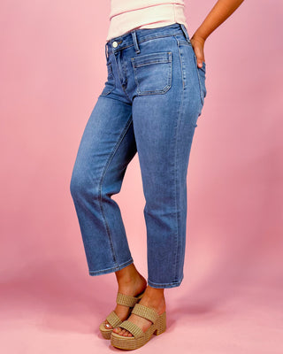 Person wearing blue jeans on a pink background