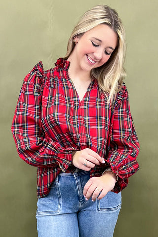 Woman wearing a red plaid shirt and blue jeans against a green background