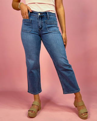 Person wearing blue jeans on a pink background