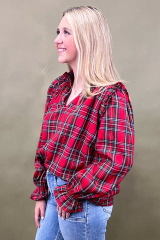 Woman wearing a red plaid shirt and blue jeans against a beige background