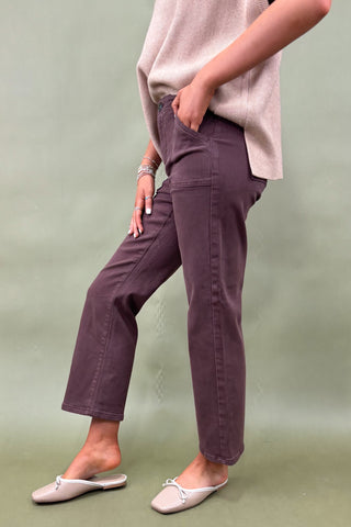 Person wearing purple pants and a light pink top against a green background