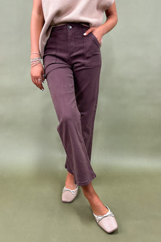Person wearing purple pants and white shoes on a green background