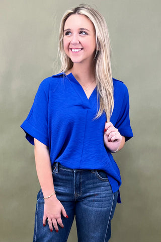 Woman wearing a blue top and jeans against a green background