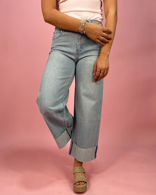 Person wearing light blue striped pants on a pink background