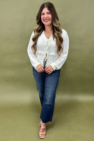 Woman wearing a white blouse and blue jeans against a green background