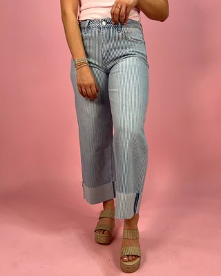 Person wearing blue striped pants on a pink background