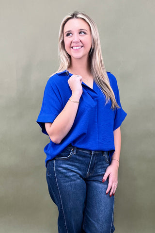 Woman wearing a blue top and jeans against a beige background