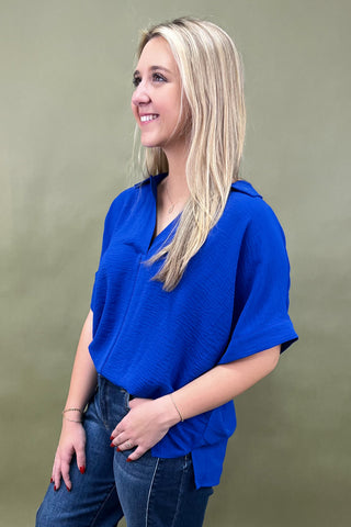 Woman wearing a blue top and jeans against a green background