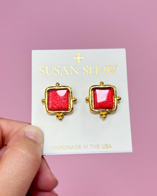 Red square earrings with gold accents on a Susan Shaw branded card against a pink background