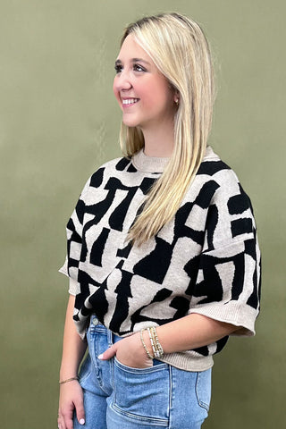 Woman wearing a black and white patterned sweater against a green background