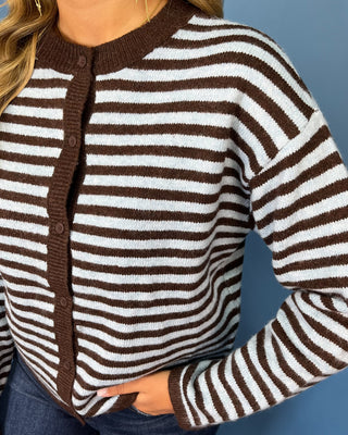 a brown and white horizontally striped knit cardigan with a dark brown button placket and ribbed collar, cuffs,