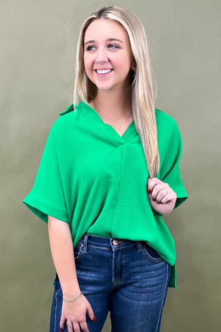 Woman wearing a green top and blue jeans against a beige background