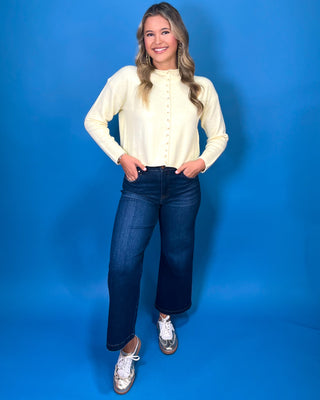 Soft butter yellow button-front knit cardigan with long sleeves, round neckline, and a relaxed cropped fit.