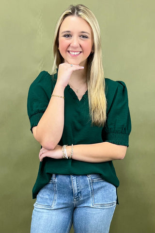 Woman wearing a green top and blue jeans against a green background
