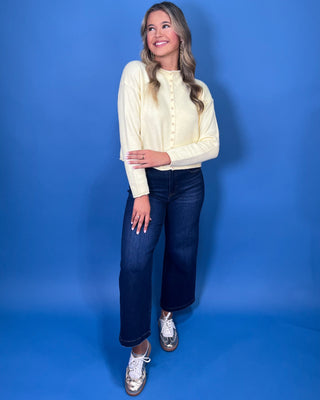Soft butter yellow button-front knit cardigan with long sleeves, round neckline, and a relaxed cropped fit.