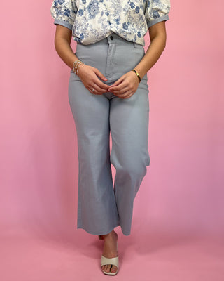 Person wearing a floral blouse and light blue jeans on a pink background