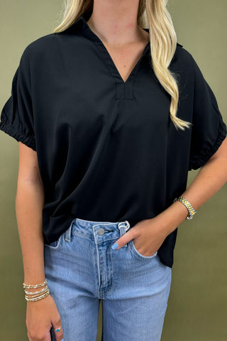 Person wearing a black shirt and blue jeans with a green background