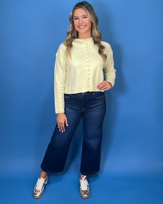 Soft butter yellow button-front knit cardigan with long sleeves, round neckline, and a relaxed cropped fit.
