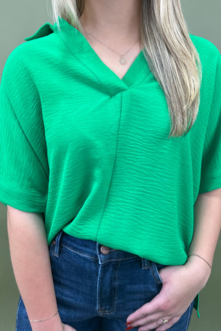 Person wearing a green top and blue jeans against a neutral background