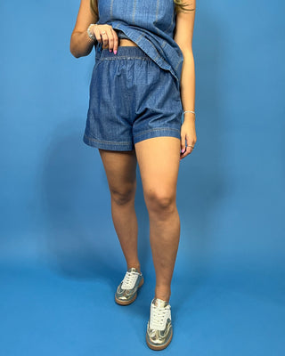 A woman modeling a sleeveless blue denim romper with matching denim shorts