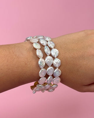 Pearl bracelet on a wrist with a pink background