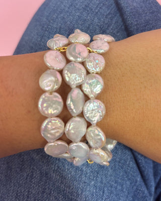 Pearl bracelet on a wrist with a pink and blue background