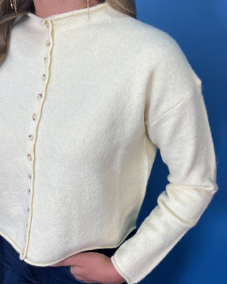 Soft butter yellow button-front knit cardigan with long sleeves, round neckline, and a relaxed cropped fit.