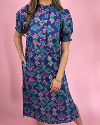 Woman wearing a blue floral dress against a pink background