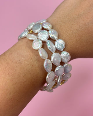 Pearl bracelet on a wrist with a pink background