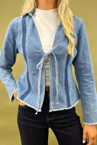 Woman wearing a blue denim jacket and dark jeans on a green background