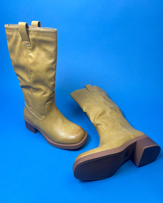 A tan leather knee-high boot with a brown stacked heel, held up against a solid blue background.