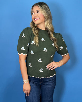 Forest green floral knit sweater top with puff sleeves, blue embroidered flowers, and scalloped contrast trim.