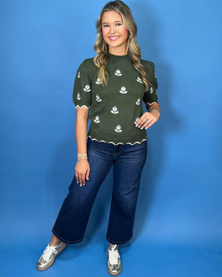 Forest green floral knit sweater top with puff sleeves, blue embroidered flowers, and scalloped contrast trim.