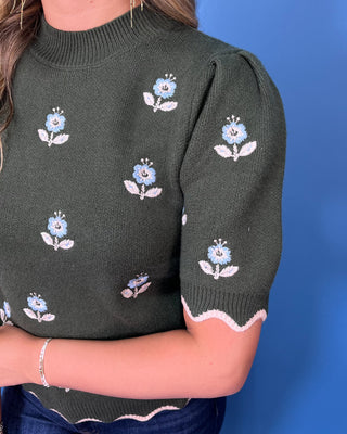 Forest green floral knit sweater top with puff sleeves, blue embroidered flowers, and scalloped contrast trim.