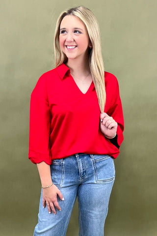 Woman wearing a red blouse and blue jeans against a green background