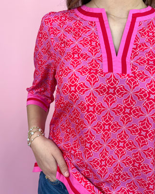 Person wearing a red and pink patterned kurta against a pink background