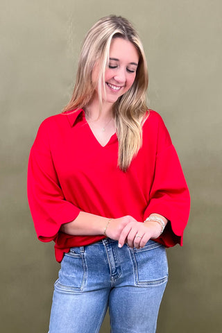 Woman wearing a red blouse and blue jeans against a green background