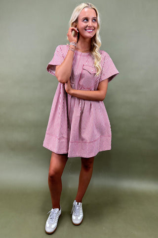 Woman wearing a pink and white striped dress against a green background