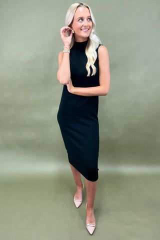 Woman wearing a black sleeveless dress against a green background