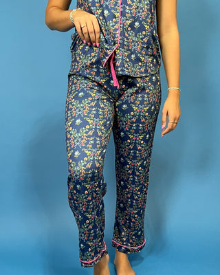 A person wearing a matching floral pajama set with a dark navy base and small multicolored flowers, featuring pink trim an