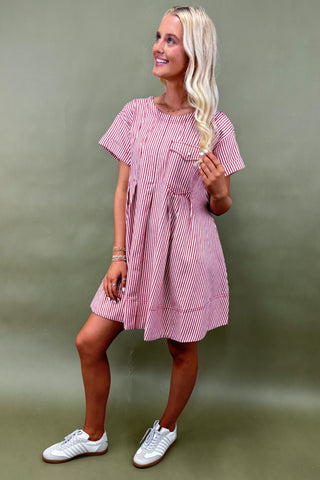 Woman wearing a pink and white striped dress against a green background