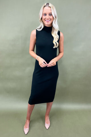 Woman wearing a black sleeveless dress against a green background