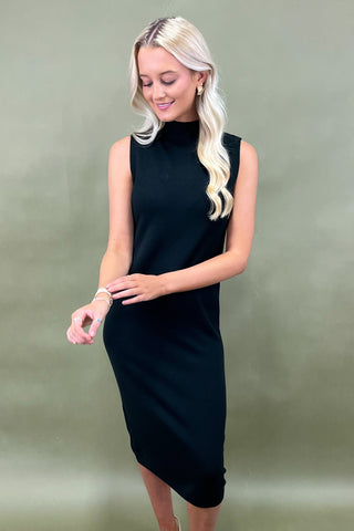 Woman wearing a black sleeveless dress against a green background