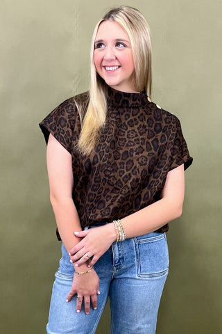 Woman wearing a leopard print top and blue jeans against a green background