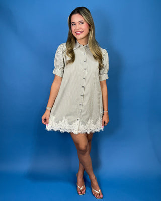 A woman modeling a short-sleeve button-front shirt dress with thin vertical stripes and a lace hem